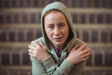 Portrait of sad schoolgirl sitting alone on staircase in school