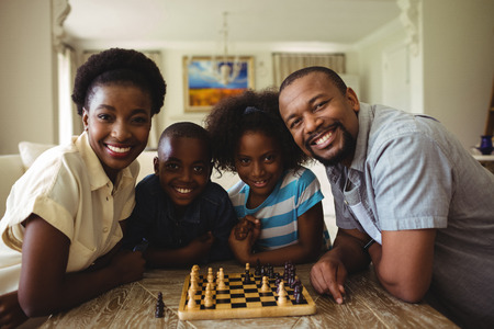 Portrait of family playing chess together at home in the living room at homeの写真素材