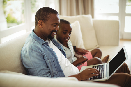 Father and son using laptop in living room at homeの写真素材