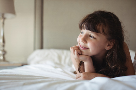 Siblings looking away in bed at homeの写真素材