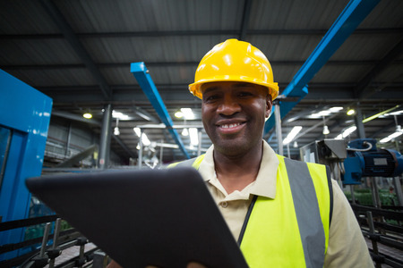 Portrait of smiling factory worker using a digital tablet in the factory
