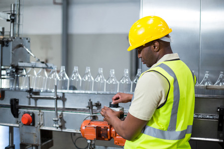 Factory worker operating machine in drinks production plantの写真素材