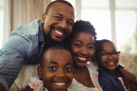 Portrait of parents and son sitting on sofa in living room at homeの写真素材