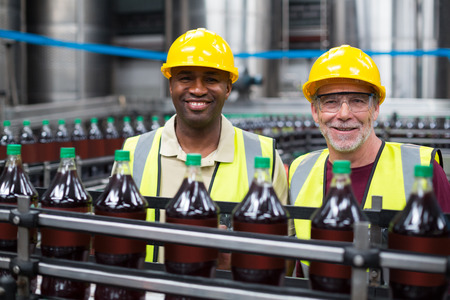 Smiling factory workers monitoring drinks production line in the factoryの写真素材