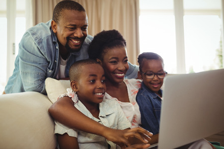 Parents and kids using laptop in living room at homeの写真素材