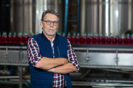 Portrait of factory worker standing with his arms crossed in drinks production plantの写真素材