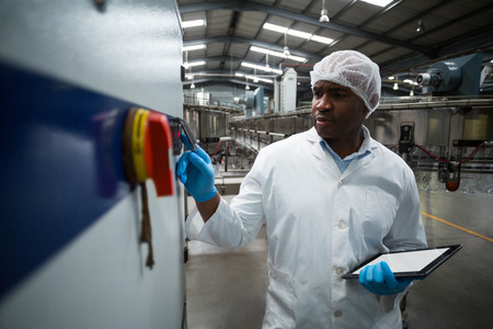 Factory engineer operating machine in drinks production plantの写真素材