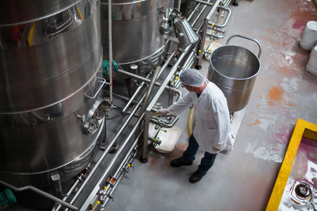 Factory engineer monitoring storage tank in bottle factoryの写真素材