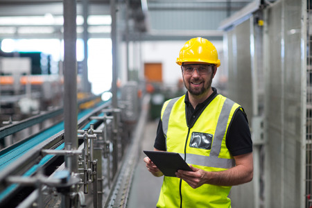 Portrait of smiling factory worker using a digital tablet in factoryの写真素材