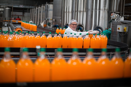Factory engineer monitoring filled juice bottle on production line in bottle factoryの写真素材