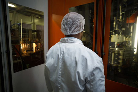 Factory engineer looking at machine in bottle factory