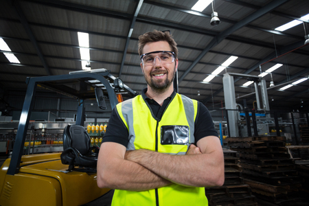 Portrait of factory worker standing with arms crossed in factoryの写真素材