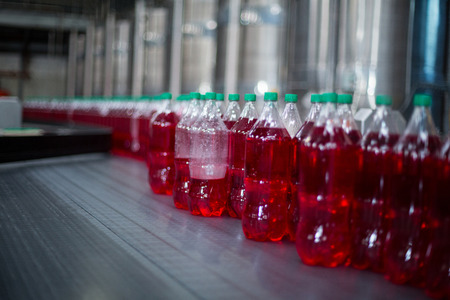 Close-up of bottles of juices processing on conveyor belt in factoryの写真素材