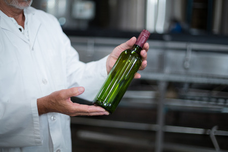 Mid-section of factory worker examining a bottle in factoryの写真素材