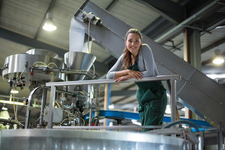 Portrait of female factory worker standing near a storage tank at drinks production factoryの写真素材