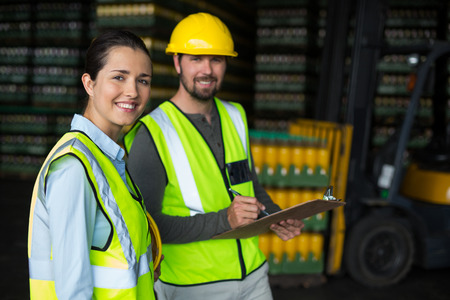 Portrait of factory workers discussing inventory over clipboard at drinks production factoryの写真素材