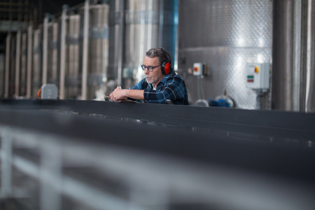 Male factory worker maintaining record on clipboard in drinks production factoryの写真素材