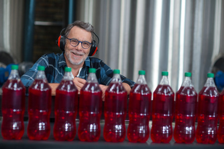 Portrait of male factory worker monitoring cold drink bottles at drinks production factory