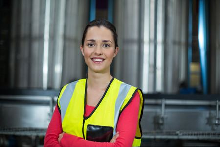 Portrait of female factory worker standing with arms crossed at drinks production factoryの写真素材