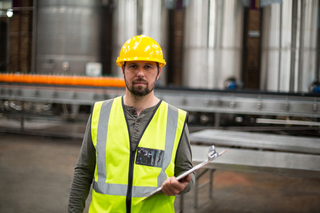 Portrait of factory worker holding clipboard in drinks production factoryの写真素材