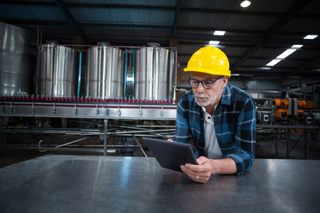 Factory worker using digital tablet at drinks production factoryの写真素材