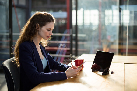 Female business executive using mobile phone at desk in office