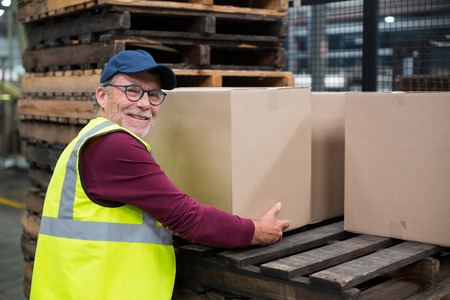 Factory worker loading cardboard boxes on trolley in drinks production factoryの写真素材
