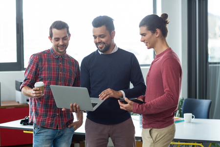 Businesspeople having discussion over laptop in officeの写真素材