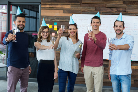 Portrait of businesspeople showing glasses of champagne in officeの写真素材