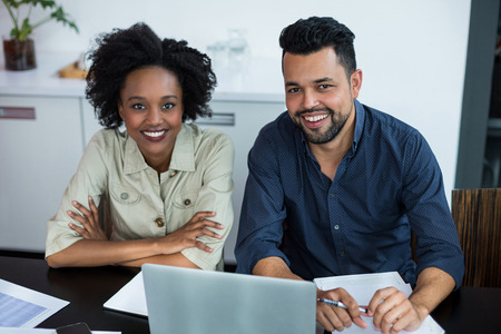 Portrait of smiling two business executives working on laptop in officeの写真素材