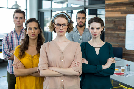 Portrait of business executives standing with arms crossed in officeの写真素材