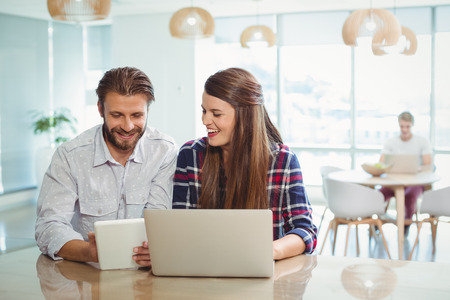 Business executives using digital tablet and laptop in officeの写真素材