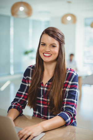Portrait of female business executive using laptop in officeの写真素材