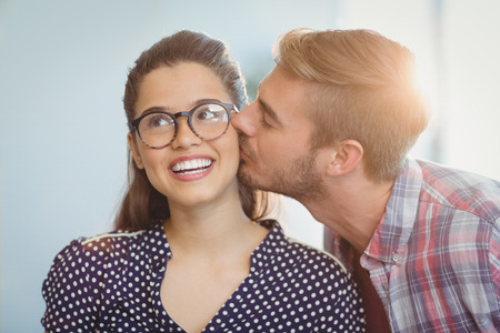 Affectionate man kissing woman in officeの写真素材