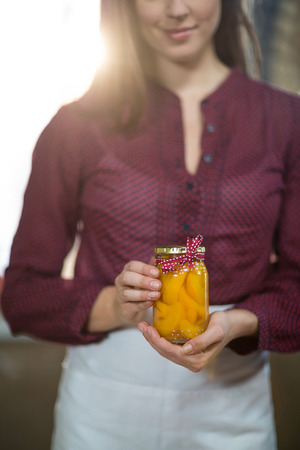 Shop assistant holding a jar of pickle in grocery shopの写真素材