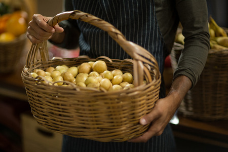 Mid-section of a vendor holding basket of potatoes at the grocery storeの写真素材