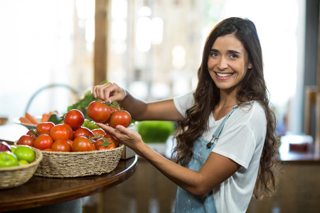 Portrait of a picking woman choosing fresh tomatoes from the basketの写真素材
