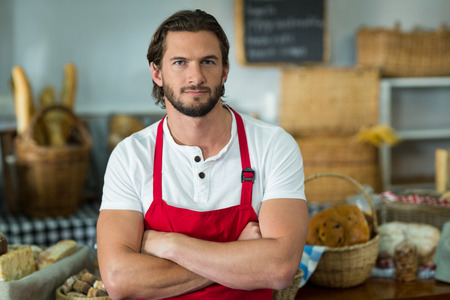 Portrait of bakery staff standing with arms crossed at counter in bake shopの写真素材