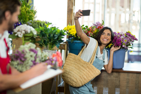 smiling woman taking a selfie at florist shopの写真素材
