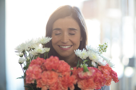 Smiling woman holding a bouquet with eyes closed in the florist shopの写真素材