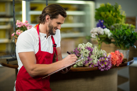 Florist writing on the clipboard at florist shopの写真素材
