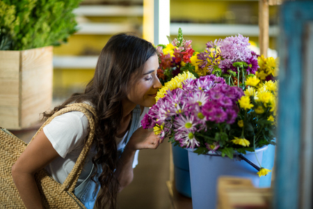 Woman smelling a bunch of flowers at florist shopの写真素材