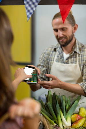 Woman making a payment by using NFC technology in the grocery storeの写真素材