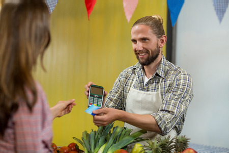 Woman making a payment by using NFC technology in the grocery storeの写真素材