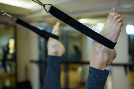 Woman performing stretching exercise on reformer in gym
