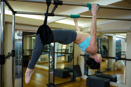 Determined woman performing stretching exercise on pilates cadillac in gym