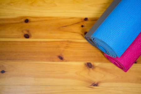 Rolled-up exercise mat on wooden floor in gymの写真素材