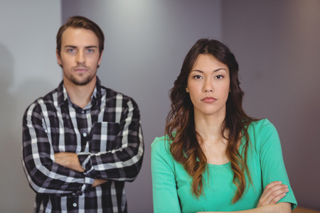 Portrait of male and female executives standing with arms crossed in officeの写真素材