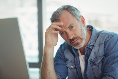Portrait of worried male executive sitting in officeの写真素材
