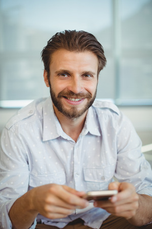Portrait of male executive using mobile phone in officeの写真素材